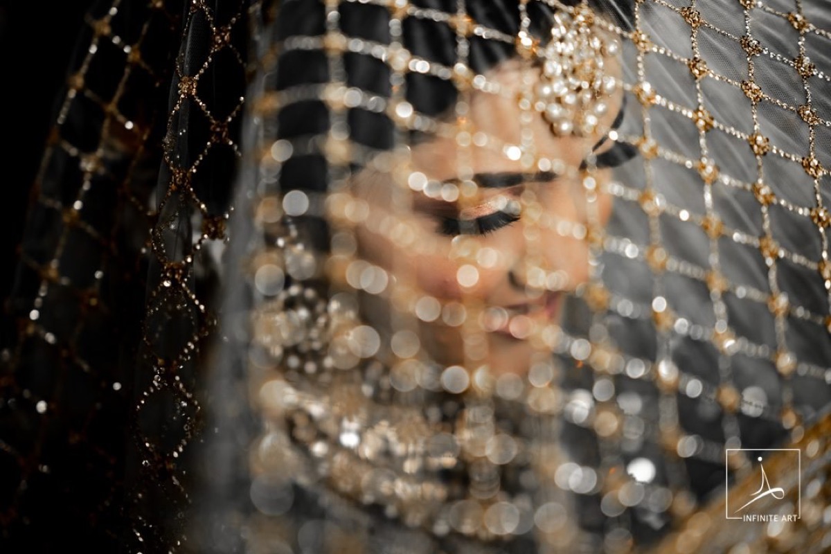 Amina with her eyes closed beneath a gold-latticed veil, the beads catching the light